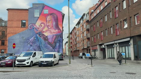 A-street-in-Malmo-with-street-art-on-the-wall-of-a-building,-showcasing-urban-creativity