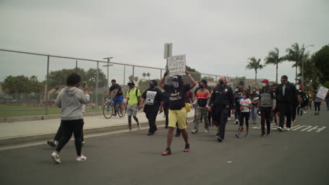 Marching-during-a-protest-in-the-middle-of-the-street-with-a-group-of-people-by-a-high-school