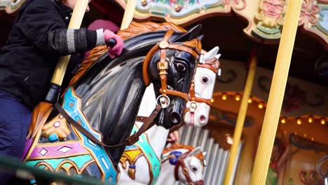 Young-Caucasian-girl-rides-horse-on-historic-classic-carousel-Dyrekarrusellen,-Tivoli-Gardens,-Copenhagen,-Denmark,-close-up-slow-motion