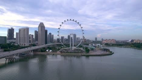 Aerial-video-of-the-Singapore-city-skyline-featuring-the-Singapore-Flyer-observation-ferris-wheel,-Marina-Bay-Sands-hotel-and-Gardens-by-the-Bay-at-dawn