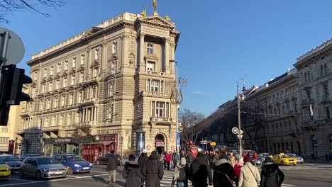 Early-morning-shoppers-cross-the-road-at-a-busy-Budapest-city-intersection,-on-a-glorius-winter-morning