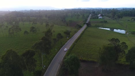 Toma-Aérea-De-Un-Porsche-Cayman-En-Movimiento-En-Las-Carreteras-Colombianas-Durante-Una-Tarde-Soleada-Y-Brillante