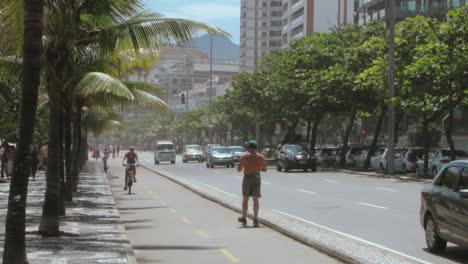 People-walking,-running,-cycling-at-Calçadão-at-Ipanema-bright-sunny-day,-tilt-shot