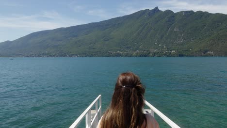 Young-brunette-woman-walks-towards-sea-in-white-bridge-water-mountain-background