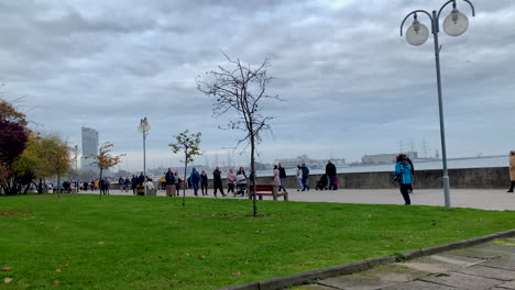 Menschen-Gehen-Auf-Dem-Strandboulevard-Spazieren,-Herbstspaziergang-An-Der-Küste,-Zeitlupe