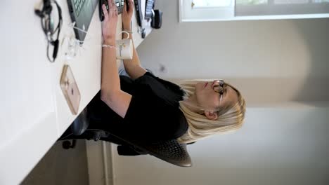 A-woman,-an-office-worker,-seated-in-a-professional-business-environment,-focuses-on-her-computer-screen,-Vertical-Video