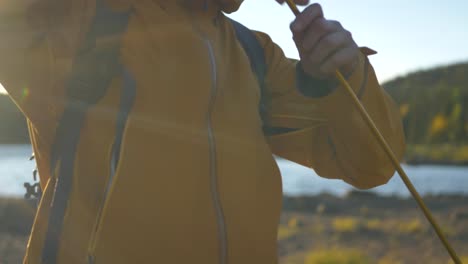 Man-in-yellow-Jacket-assembling-tent-poles-amidst-Swedish-landscape---Medium-close-up-orbit-tracking-shot