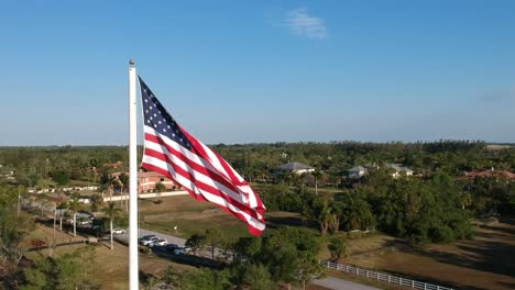 Lenta-órbita-Aérea-Alrededor-De-Una-Gran-Bandera-Estadounidense-Ondeando-Al-Viento.