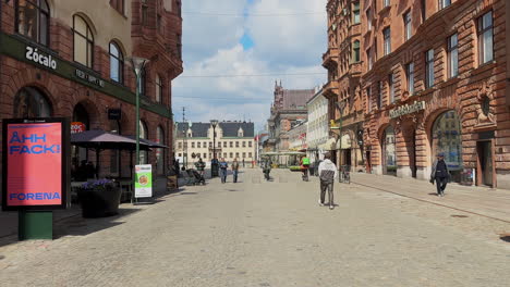 People-stroll-along-Södergatan-in-Malmö,-heading-to-and-from-Stortorget-Square,-capturing-the-bustling-urban-life-of-the-city