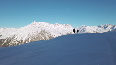 A-young-couple-of-cross-country-skiers-in-silhouette-ascending-a-slope-in-the-Austrian-Alps,-slow-motion