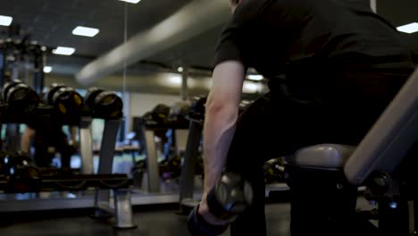 Man-lifting-dumbbells-while-looking-at-mirror-in-a-gym