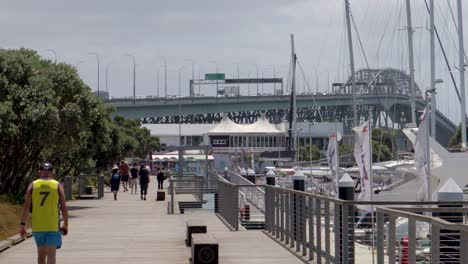 On-sunny-day-people-walking-on-street-near-harbour-bridge,-Westhaven,-Auckland,-New-Zealand