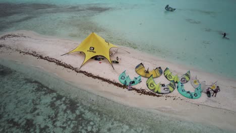 A-kitesurfing-camp-on-a-small-sandy-island-with-turquoise-waters,-aerial-view