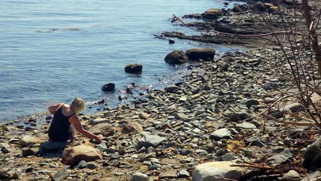 Woman-sitting-on-rocky-beach-in-Portland,-Maine