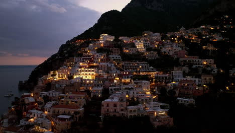 Aéreo:-Toma-Panorámica-De-Retroceso-De-Positano-En-La-Costa-De-Amalfi,-Italia-Durante-La-Puesta-De-Sol