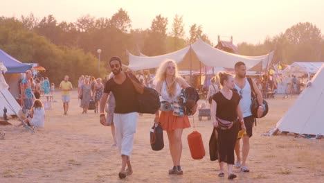 Eine-Gruppe-Cooler-Freunde,-Studenten,-Die-Bei-Goldenem-Sonnenuntergang-Mit-Ihren-Taschen-Zum-Festival-Camping-In-Zeitlupe-Gehen