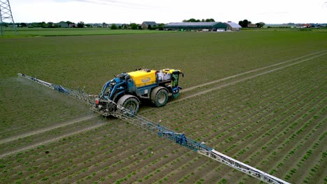 Drone-footage-of-a-self-propelled-field-sprayer-at-work,-drone-flies-sideways-with-the-machine