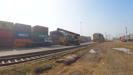 Weite-Aufnahme-Eines-Krans,-Der-Einen-Großen-Lagercontainer-Auf-Einen-Güterwagen-In-Einem-Trockenbahnhafen-Lädt