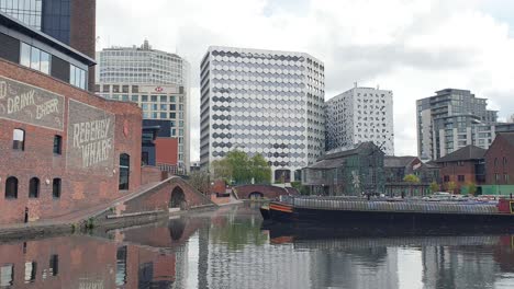 Scenic-view-overlooking-canal-with-barge-boat-at-Regency-Wharf-in-the-city-centre-of-Birmingham,-the-midlands-of-England-UK