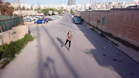 Active-track-drone-shot-of-a-young,-athletic,-caucasian-woman-inline-skating-on-the-streets-feeling-free-and-joyful