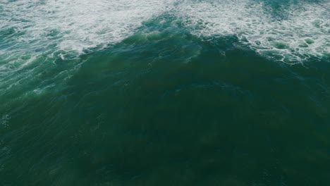 Vista-Aérea-De-Las-Olas-Del-Océano-Verde-Con-Patrones-De-Espuma-Blanca