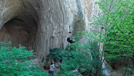 Bungee-jumper-dangles-on-rope-lowered-to-floor,-Eyes-of-God-cave