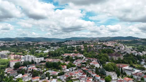 Panoramic-aerial-view-of-Guimarães-city-center-in-northern-Portugal,-surrounded-by-lush-greenery-and-hills