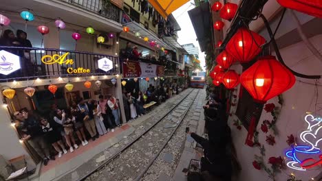 Train-travelling-along-Hanoi-Train-Street,-a-narrow-train-bypass-where-the-railway-tracks-almost-completely-encircle-the-buildings-on-either-side-of-the-tracks