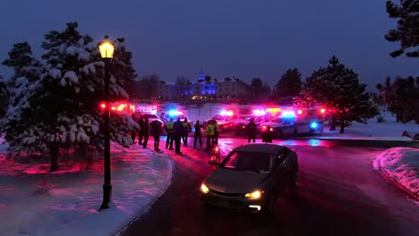 Aerial-dolly-forward-over-ambulances-with-flashing-lights-on-snowy-winter-night