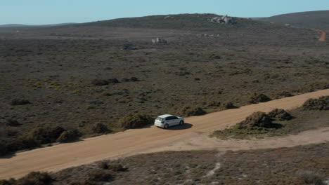 Un-Volkswagen-Polo-Tsi-Blanco-Conduciendo-A-Través-De-Un-Paisaje-Escénico-En-El-Parque-Nacional-De-La-Costa-Oeste,-Sudáfrica