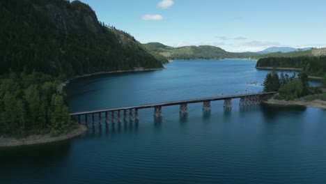 aerial-shot-over-campbell-upper-lake-trestle-bridge-on-a-sunny-day-during-spring-near-strathcona-regional-park-in-north-vancouver-island,-british-columbia,-canada