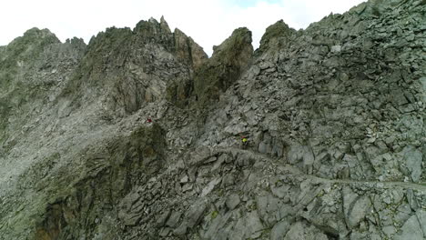 Aerial-drone-view-of-professional-mountain-trekker-walking-on-extreme-mountain-trail-close-to-cliff