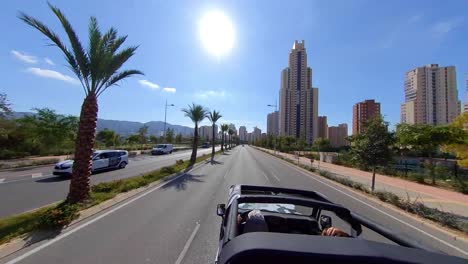 Benidorm,-España---Junio-De-2020:-Vista-En-Cámara-Rápida-De-Un-Hombre-Conduciendo-Un-Automóvil-Con-Techo-Abierto-Acelerando-En-Una-Carretera-Vacía-Mientras-Conversaba-Con-Una-Mujer-En-La-Autopista-Durante-Un-Día-Soleado-En-La-Ciudad