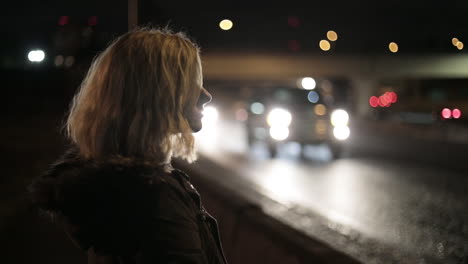 A-girl-stands-by-a-highway-at-night