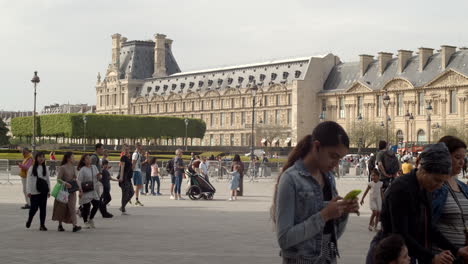 Touristen,-Die-Abends-Im-Innenhof-Des-Louvre-Herumlaufen,-Mit-Dem-Tuileriengarten-Im-Hintergrund