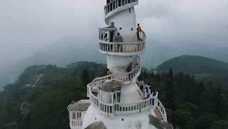 Mehrere-Touristen-Gehen-Die-Wendeltreppe-Hinauf-Und-Genießen-Die-Wunderschöne-Aussicht-Vom-Hohen-Weißen-Ambuluwa-Turm,-Während-Im-Hintergrund-Die-Natur-In-Nebel-Gehüllt-Ist