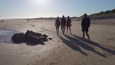 Cuatro-Amigos-Caminan-Por-Una-Playa-Muy-Arenosa---Australia