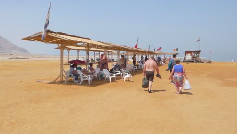 People-relaxing-under-a-shade-on-a-beach-in-Dead-Sea,-Israel