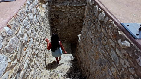 Beautiful-woman-walking-down-ancient-stone-staircase-of-castle,-back-slow-motion-view