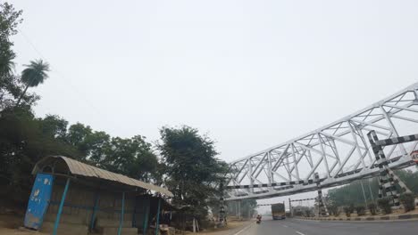 Toma-Amplia-En-ángulo-Bajo-De-Un-Puente-Ferroviario-De-Acero-Que-Cruza-Una-Carretera-En-La-India