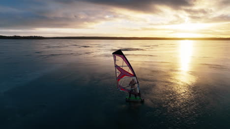 Drohne-Folgt-Eiswindsurfer-Von-Links-Nach-Rechts-Im-Farbenfrohen-Wintersonnenuntergang