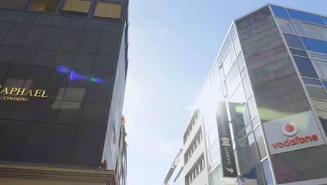 Walking-through-city,-multistorey-buildings-along-street-and-tilt-up-reveal-tall-tower-crane-against-sky