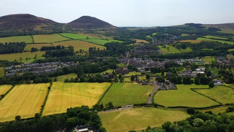 Beautiful-aerial-scene-of-Scottish-countryside-in-the-borders-region-of-Scotland-in-spring-summer-time-season-panning-to-Melrose-town-on-a-bright-sunny-day