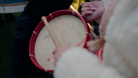 Persona-Tocando-Un-Tambor-Rojo-Con-Palos-De-Madera-Durante-Un-Evento-Musical-Al-Aire-Libre.