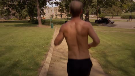 following-young-shirtless-man-running-from-behind-the-back-at-park-on-a-hot-sunny-day