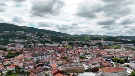 Aerial-view-of-the-center-of-Guimarães,-Portugal,-nestled-in-a-mountainous-landscape-under-a-cloudy-sky