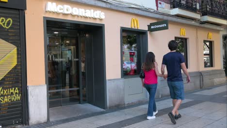 La-Gente-Entra-En-La-Cadena-De-Restaurantes-De-Hamburguesas-De-Comida-Rápida-Multinacional-Americana,-McDonald&#39;s,-En-Madrid,-España