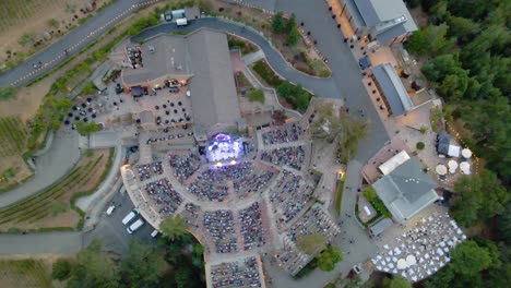 Aerial-view-of-above-a-stage-with-colorful-lights-at-the-mountain-winery-venue-in-California---rising,-drone-shot