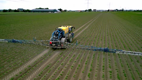 A-self-propelled-field-sprayer-irrigates-the-field,-the-drone-flies-from-the-back-to-the-side-of-the-machine