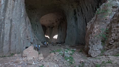 Los-Turistas-Entran-En-La-Enorme-Entrada-A-Los-Ojos-De-Dios-Cueva-Kárstica-Prohodna